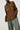 Person wearing a brown shirt and green pants on a white background