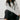Woman sitting on a chair wearing a light gray sweater and black pants.