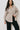 Woman wearing a beige shirt over a black top against a white background