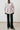 Person wearing a light pink blazer and black pants against a white background