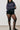 Person wearing a dark blue sweater, black shorts, and black tights against a plain background