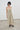 A woman modeling saga midi dress with thin straps and a smocked bodice, paired with black loafers and sunglasses, standing against a plain white wall.