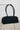 A black fabric duffel-style handbag with two long shoulder straps, displayed hanging from a clear stand in a minimalist indoor setting.